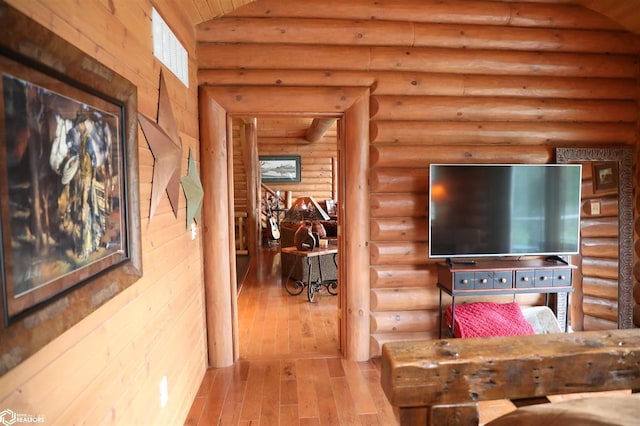 hallway featuring visible vents, vaulted ceiling, and wood finished floors