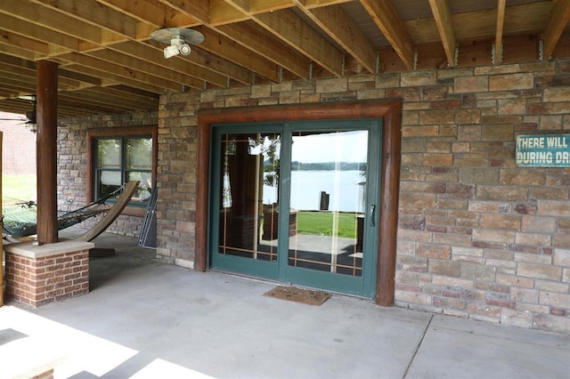 doorway to property featuring a patio area, ceiling fan, and a water view