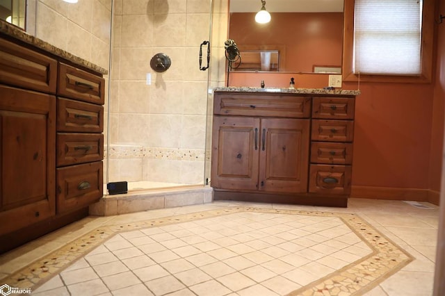 bathroom with baseboards, vanity, a shower stall, and tile patterned floors