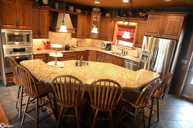 kitchen featuring a kitchen island, stainless steel appliances, a sink, and decorative light fixtures