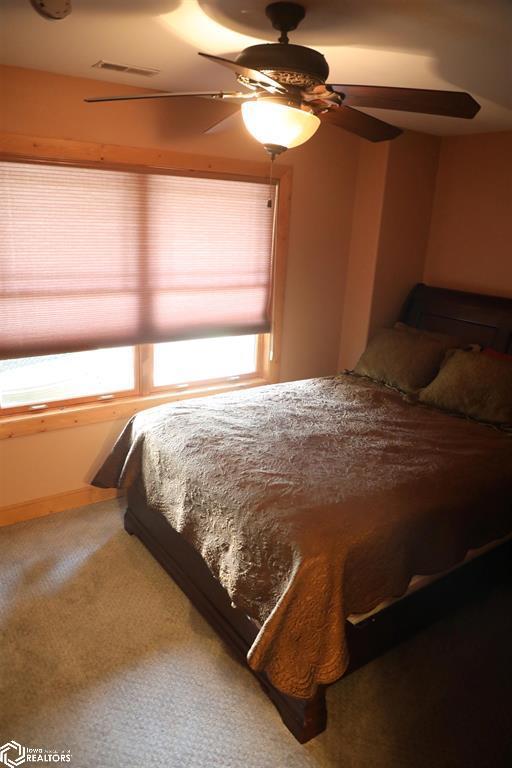 carpeted bedroom with a ceiling fan and visible vents