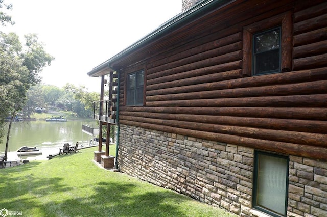 view of home's exterior with stone siding, a yard, a chimney, and a water view