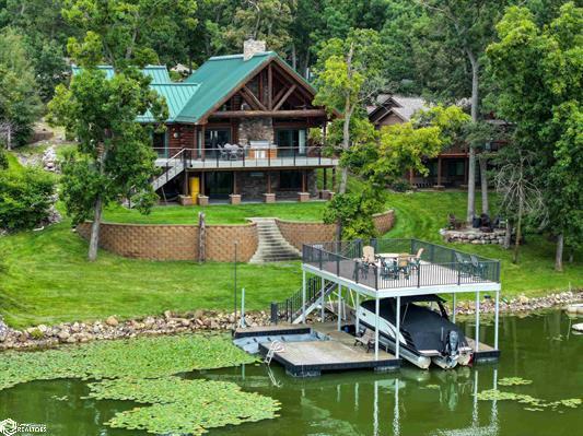 view of dock with a yard, stairway, a deck with water view, and boat lift