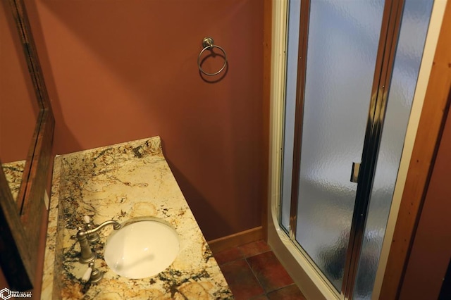 full bathroom featuring a stall shower, tile patterned flooring, vanity, and baseboards