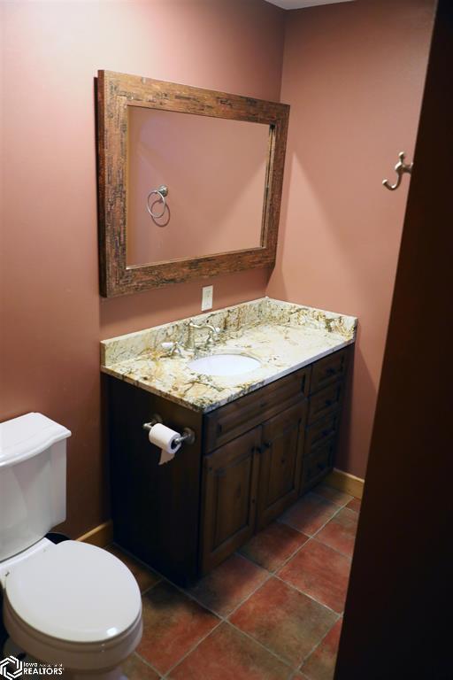 bathroom featuring toilet, tile patterned flooring, vanity, and baseboards