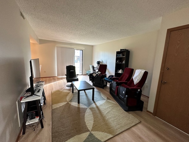 living room with a textured ceiling, light wood finished floors, and visible vents