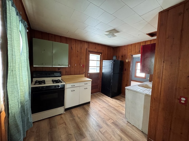 kitchen with black refrigerator, light hardwood / wood-style flooring, and gas stove