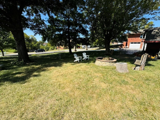 view of yard featuring a garage and an outdoor fire pit