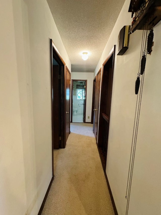 hallway featuring a textured ceiling and light colored carpet