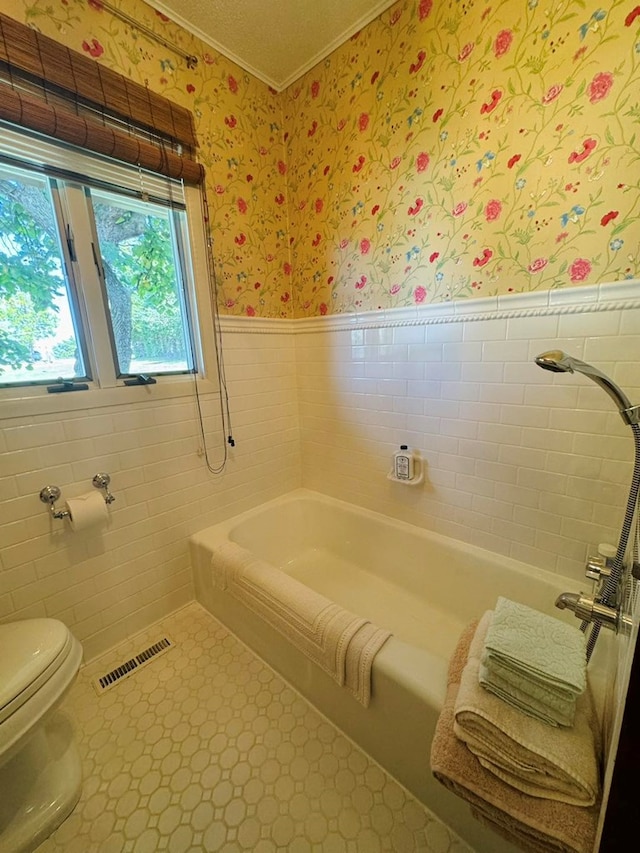 bathroom featuring tile patterned flooring, toilet, and a bath