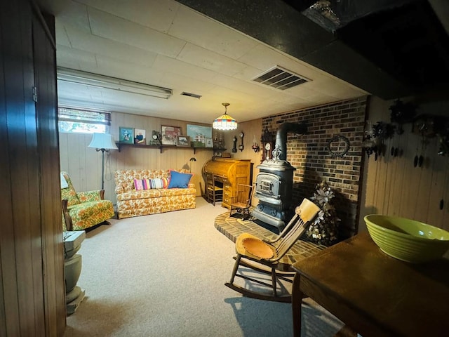 recreation room with carpet flooring, a wood stove, and wood walls