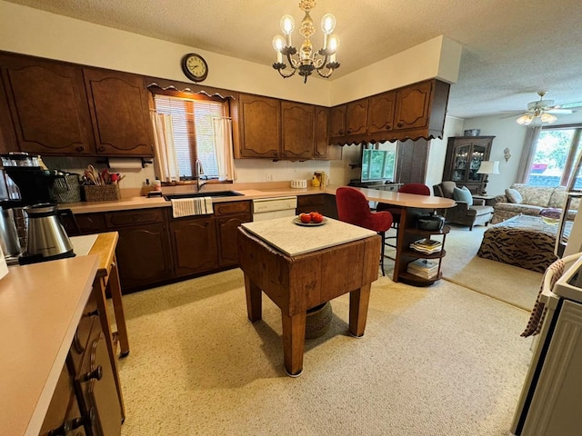 kitchen with sink, ceiling fan with notable chandelier, hanging light fixtures, and a textured ceiling