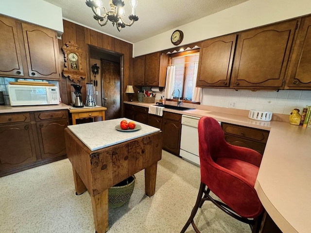 kitchen featuring sink, a chandelier, white appliances, decorative backsplash, and a kitchen island