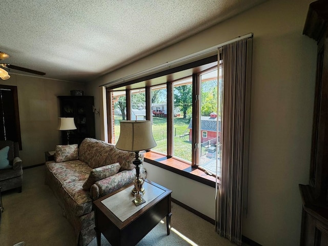 carpeted living room featuring ceiling fan, plenty of natural light, and a textured ceiling