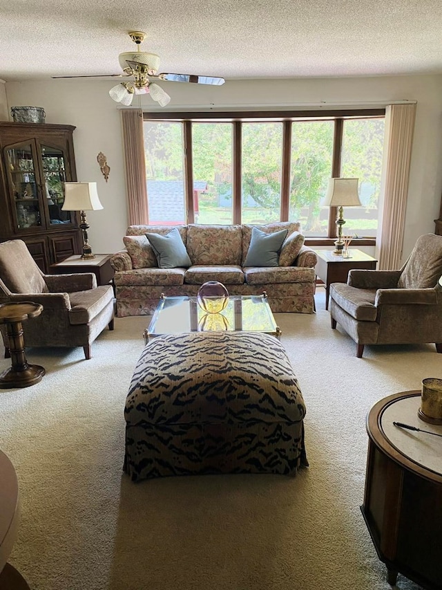 living room featuring carpet, ceiling fan, and a textured ceiling