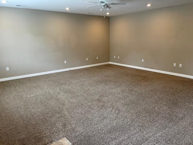 carpeted empty room with ceiling fan and a textured ceiling