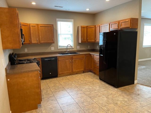 kitchen with sink, light colored carpet, and black appliances