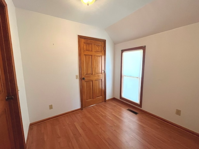 spare room with light hardwood / wood-style flooring and vaulted ceiling