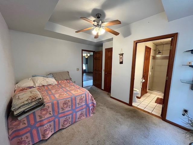 bedroom with ensuite bathroom, ceiling fan, a raised ceiling, and light carpet