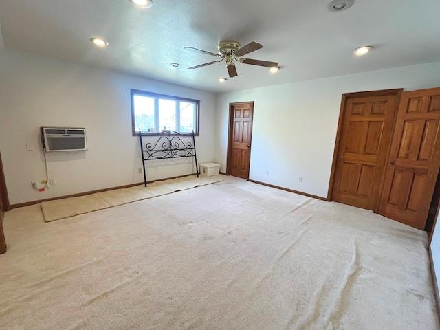 unfurnished bedroom with a wall mounted air conditioner, ceiling fan, and light colored carpet