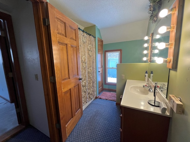 bathroom with a textured ceiling, tile patterned flooring, vanity, and lofted ceiling