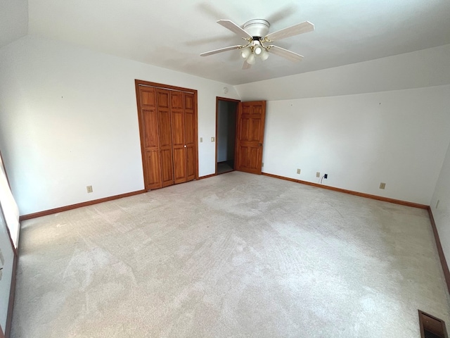 unfurnished bedroom with ceiling fan, lofted ceiling, light carpet, and a closet