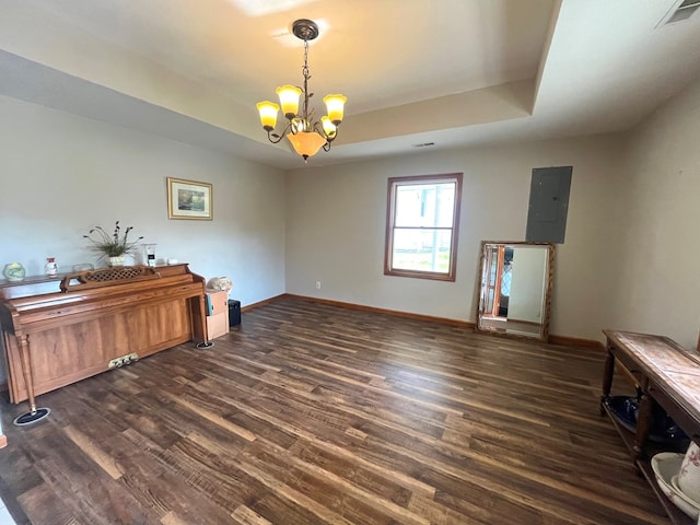 interior space featuring a tray ceiling, electric panel, dark wood-type flooring, and a chandelier