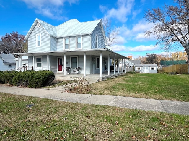 farmhouse featuring covered porch, a front yard, and a storage shed