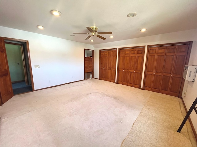 unfurnished bedroom featuring two closets, light colored carpet, and ceiling fan