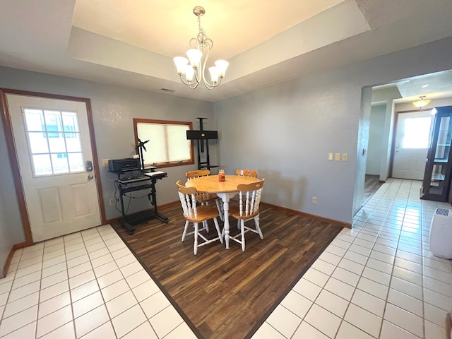 tiled dining area featuring a tray ceiling and a chandelier