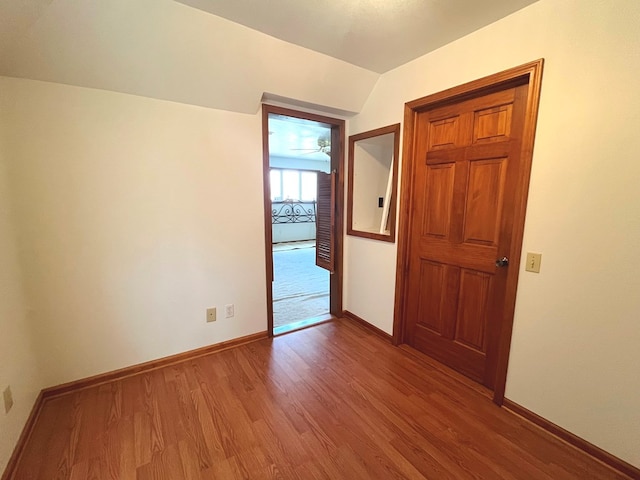 unfurnished room with hardwood / wood-style flooring and vaulted ceiling