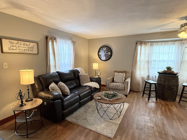 living room with ceiling fan, baseboards, wood finished floors, and a healthy amount of sunlight