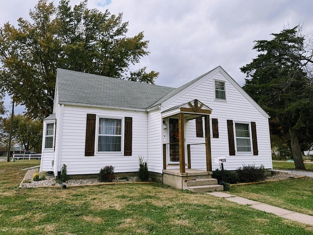 bungalow-style house featuring a shingled roof and a front lawn