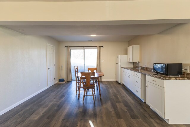 500 W Santa Fe St, Marceline, MO 64658 - kitchen with white cabinetry, sink, dark hardwood / wood-style floors, white fridge, and dark stone counters