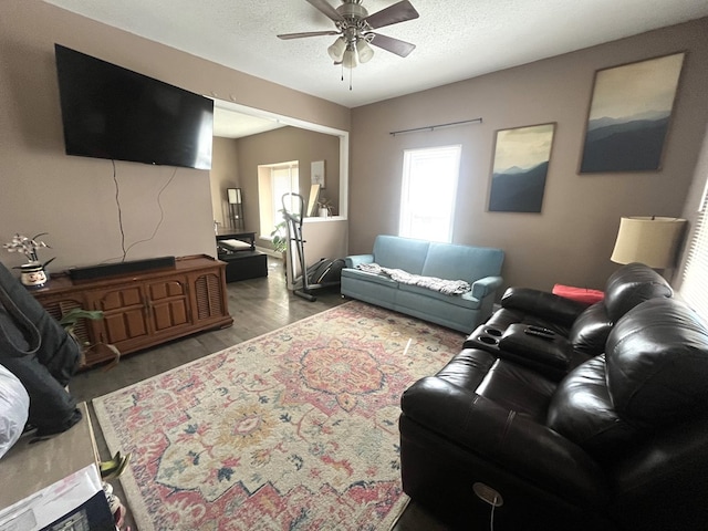 living area with ceiling fan, wood finished floors, and a textured ceiling