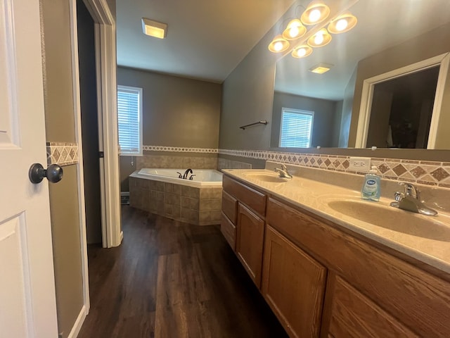 full bath with a sink, wood finished floors, a bath, and double vanity