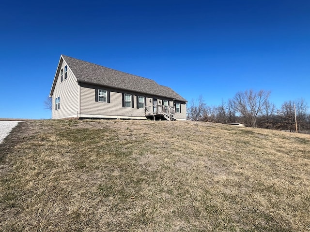 exterior space with a yard and a shingled roof