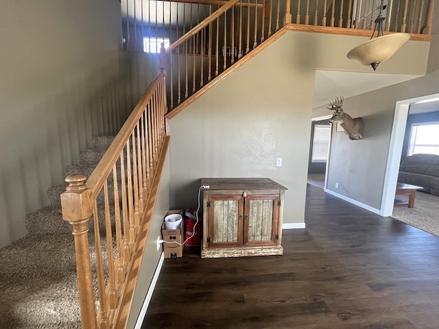 staircase featuring a high ceiling, baseboards, and wood finished floors