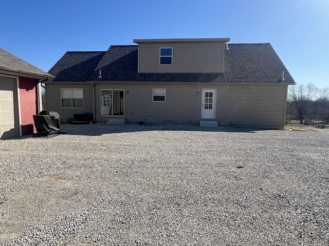 back of house with a garage, a shingled roof, and entry steps