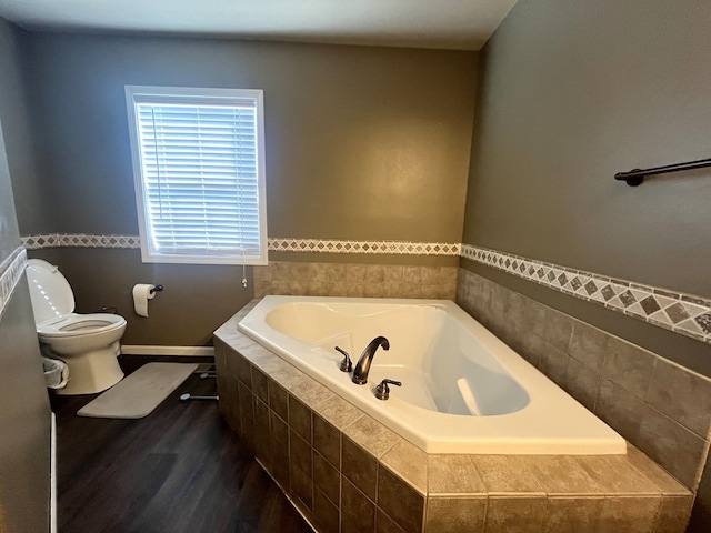 bathroom featuring a garden tub, toilet, and wood finished floors