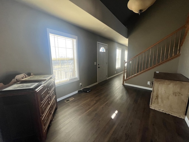 entrance foyer with visible vents, baseboards, dark wood-type flooring, and stairs