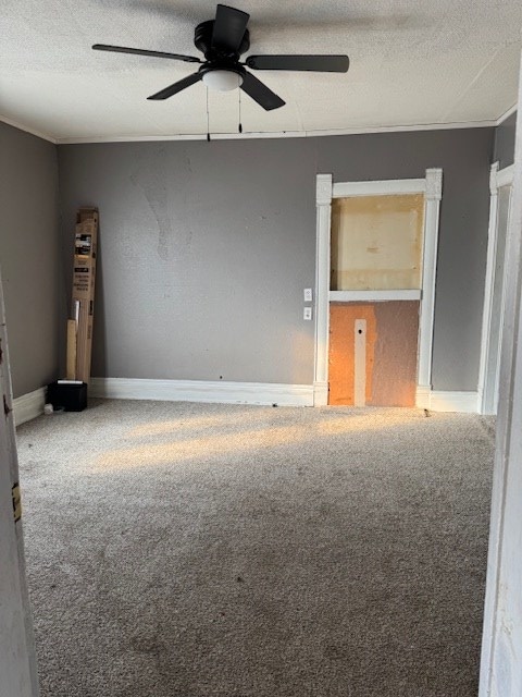 carpeted spare room featuring ceiling fan, baseboards, and a textured ceiling