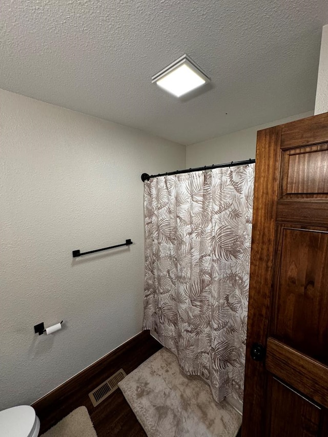 bathroom with hardwood / wood-style floors, a textured ceiling, and toilet