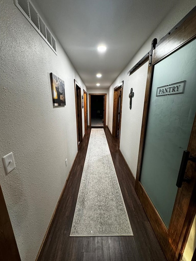 corridor featuring a barn door and dark hardwood / wood-style floors