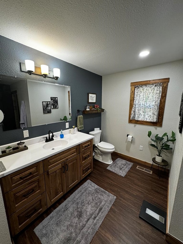 bathroom featuring hardwood / wood-style floors, vanity, toilet, and a textured ceiling