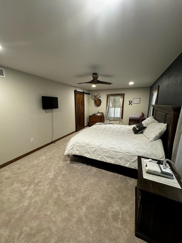 bedroom with a barn door, ceiling fan, and light colored carpet