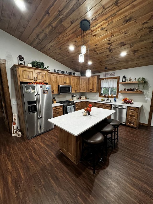 kitchen featuring sink, stainless steel appliances, dark hardwood / wood-style floors, decorative light fixtures, and a kitchen island