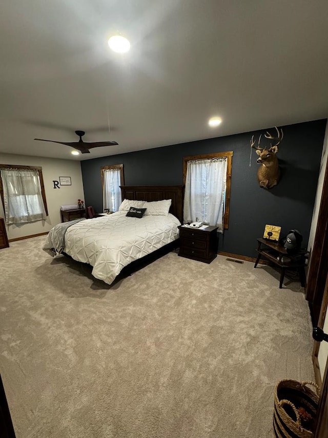 bedroom with ceiling fan, light carpet, and multiple windows