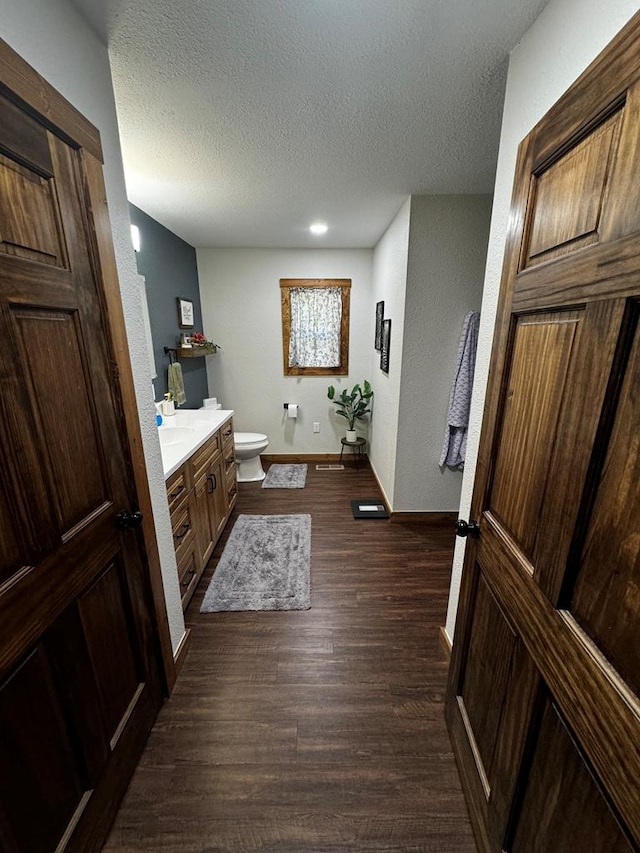 bathroom featuring vanity, toilet, wood-type flooring, and a textured ceiling