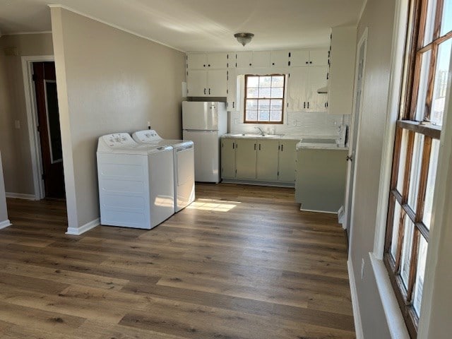 laundry room with dark wood-style flooring, cabinet space, a sink, washer and dryer, and baseboards